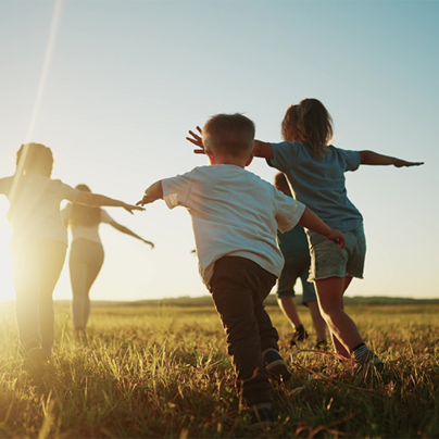 Kinder laufen im Sonnenuntergang über die Wiese 