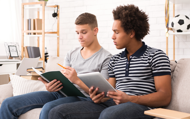 Zwei Jugendlich lernen gemeinsam auf der Couch.