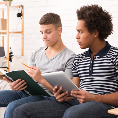 Zwei Jugendlich lernen gemeinsam auf der Couch.