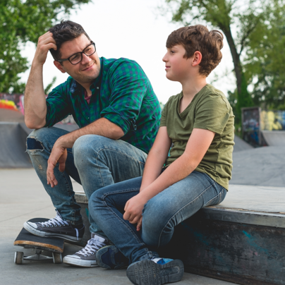 Vater und Sohn im Gespräch beim Skateboarden